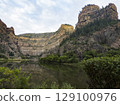 Towering Canyon Cliffs Overlooking a Serene River Valley 129100976