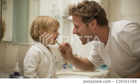 Father teaching young son dental hygiene, bonding during morning bathroom routine 129101198