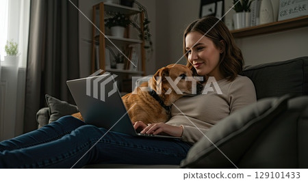 Woman and dog find comfort on couch with laptop, a moment of warm comfort 129101433
