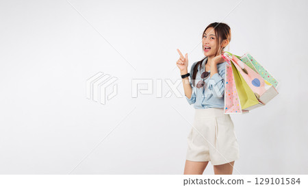 Happy young asian woman pointing finger, excited by promotion after shopping, a charming girl presenting offers for shoppers with mockup shopping bags, isolated studio white background Happy young asian woman pointing finger, excited by promotion after shopping, a charming girl presenting offers for shoppers with mockup shopping bags, isolated studio white background 129101584