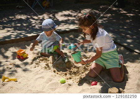 Children Playing Joyfully in a Sandbox on a Bright Summer Day 129102250