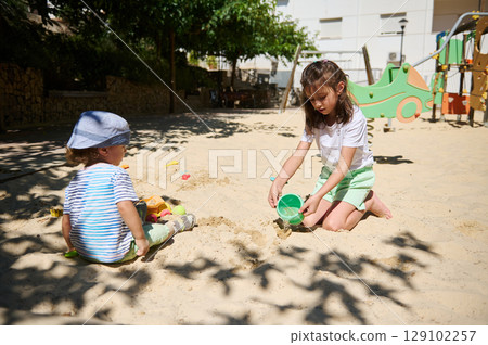Children Enjoying Playtime in a Sunny Park Sandbox During Summer 129102257