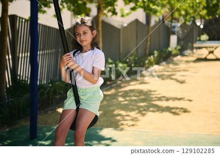 Young Girl Enjoying A Swing Ride At A Playground On A Sunny Day 129102285