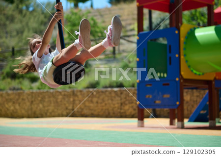 Young Girl Enjoying Playground Swing on a Bright Summer Day 129102305