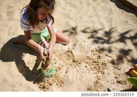 Young Girl Enjoying Sand Play Outdoors During Summer Young Girl Enjoying Sand Play Outdoors During Summer 129102314