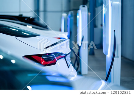 Modern electric vehicles charging at sleek station, futuristic city mobility with neon-lit charging ports 129102821