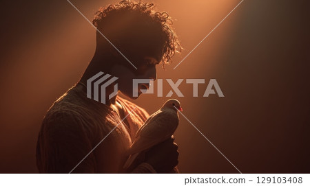 Young man holding a white dove, representing peace and spirituality Young man holding a white dove, representing peace and spirituality 129103408