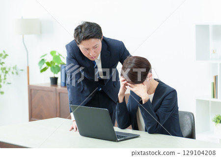 Business woman holding her head in front of a computer Business woman holding her head in front of a computer 129104208