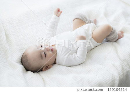 Baby lying on bed 129104214
