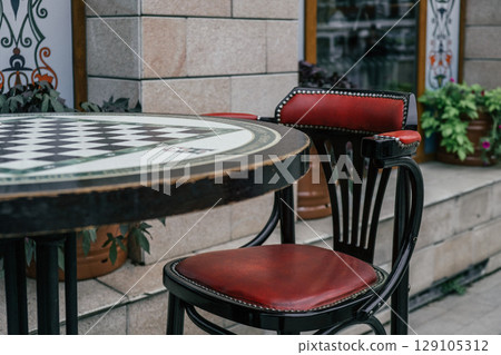 outdoor cafe seating with chess table and vibrant surroundings in lively urban area. closeup. outdoor cafe seating with chess table and vibrant surroundings in lively urban area. closeup. 129105312