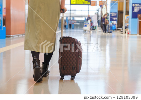 Woman walking and pushing luggage at airport, traveler, tourist Woman walking and pushing luggage at airport, traveler, tourist 129105399
