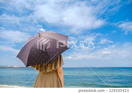 A woman looking at the sea with a parasol 129105423