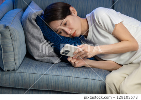 躺在沙發上使用智能手機的女人 129105578