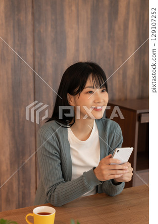 Young woman looking at her smartphone in her room 129107252
