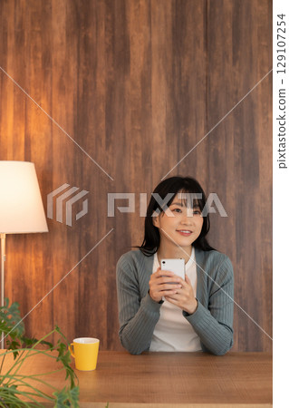 Young woman looking at her smartphone in her room 129107254