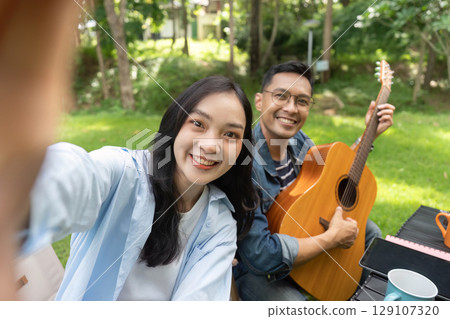Friendship and Connection. Young couple enjoying outdoor selfie with guitar. 129107320