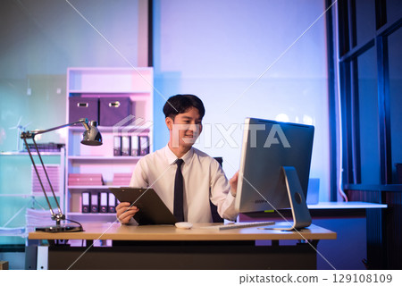 Businessman drinking coffee to get some energy for working overtime sitting at desk using computer and doing overtime Businessman drinking coffee to get some energy for working overtime sitting at desk using computer and doing overtime 129108109