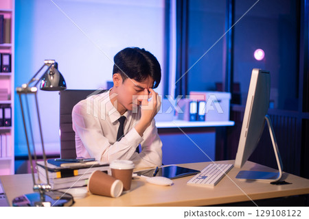 Overworked young Asian businesswoman office worker suffering from neck pain after had a long day at her office desk. 129108122