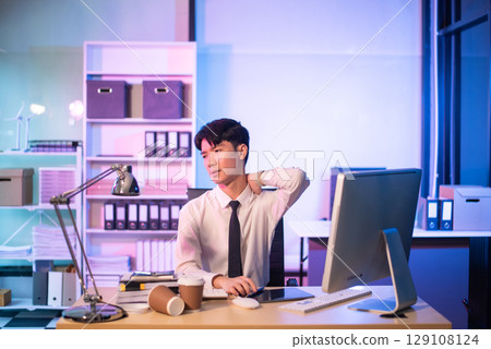 Overworked young Asian businesswoman office worker suffering from neck pain after had a long day at her office desk. Overworked young Asian businesswoman office worker suffering from neck pain after had a long day at her office desk. 129108124