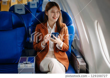 Asian woman sitting in a seat in airplane and looking out the window going on a trip vacation travel concept.Capture the allure 129108727