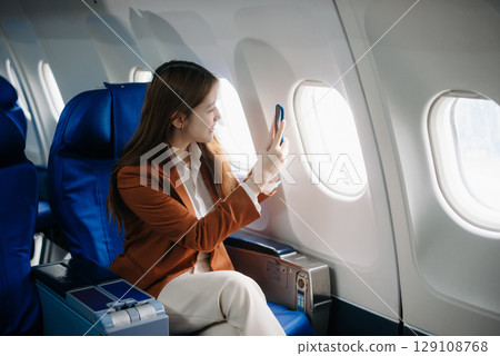 Asian woman sitting in a seat in airplane and looking out the window going on a trip vacation travel concept.Capture the allure Asian woman sitting in a seat in airplane and looking out the window going on a trip vacation travel concept.Capture the allure 129108768