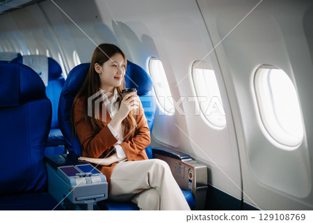Asian woman sitting in a seat in airplane and looking out the window going on a trip vacation travel concept.Capture the allure 129108769