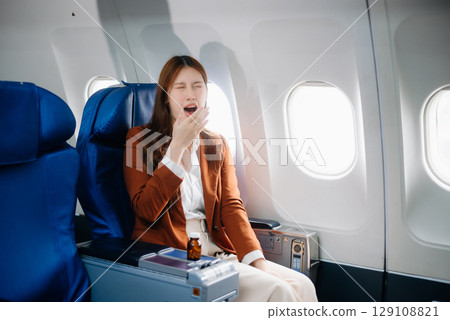Photo of a frustrated woman sitting on an airplane with her head in her hands. Asian woman sitting in a seat 129108821