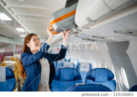 Attractive Asian female passenger of airplane sitting in comfortable seat while working laptop and tablet with mock up area using wireless connection. 129108861
