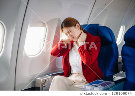Photo of a frustrated woman sitting on an airplane with her head in her hands. Asian woman sitting in a seat 129109074