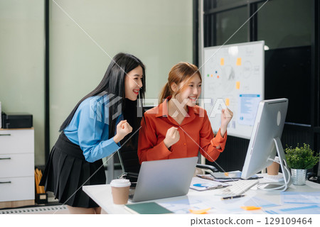 Two Asian businesswoman and man discuss investment project working and planning strategy with tablet laptop computer 129109464