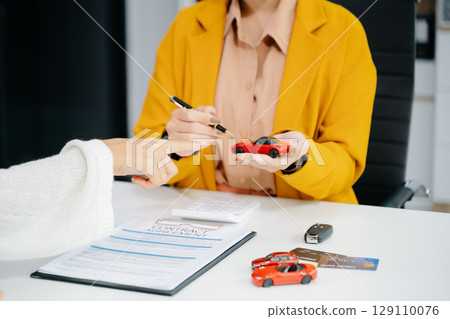 Asian people car salesman or sales manager offers to sell a car and explains of signing a car contract and signing car insurance 129110076