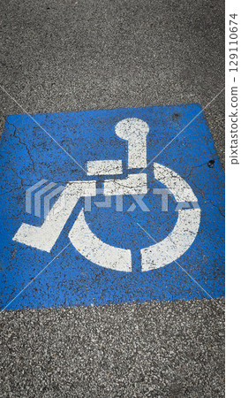 blue handicapped parking symbol painted on an asphalt surface, representing accessibility and inclusivity for people with disabilities. Rustic disabled parking sign blue handicapped parking symbol painted on an asphalt surface, representing accessibility and inclusivity for people with disabilities. Rustic disabled parking sign 129110674