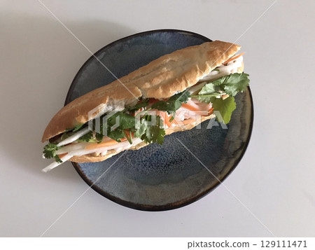 Crispy baguette sandwich filled with fresh vegetables, savory meat, and creamy dressing. A perfect balance of crunch and flavor in every hearty and satisfying bite. 129111471