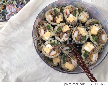 Delicious kimbap rolls filled with fresh vegetables, seasoned rice, and savory proteins, all wrapped in crisp seaweed. A perfect combination of flavor and texture in every bite. 129111472
