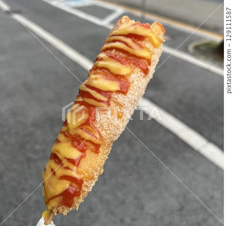 Korean corn dog, a crispy snack coated in a sweet batter, often stuffed with sausage, cheese, or both. Topped with sugar, ketchup, or mustard for a delightful mix of flavors and textures. Korean corn dog, a crispy snack coated in a sweet batter, often stuffed with sausage, cheese, or both. Topped with sugar, ketchup, or mustard for a delightful mix of flavors and textures. 129111587