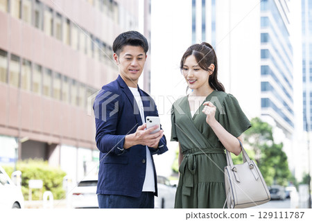 A couple looking at a smartphone in the city 129111787