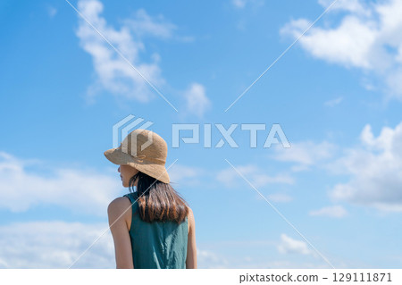 一位戴著草帽、藍天的女子 129111871