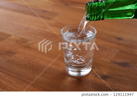 Korean Soju - Pouring chilled Korean Soju, a traditional Korean distilled alcoholic beverage, into a glass Korean Soju - Pouring chilled Korean Soju, a traditional Korean distilled alcoholic beverage, into a glass 129111947