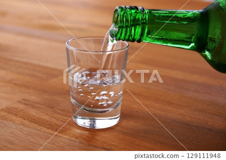 Korean Soju - Pouring chilled Korean Soju, a traditional Korean distilled alcoholic beverage, into a glass Korean Soju - Pouring chilled Korean Soju, a traditional Korean distilled alcoholic beverage, into a glass 129111948