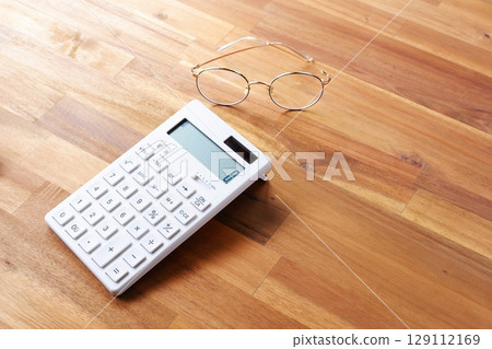 Calculator - A white calculator on a table Calculator - A white calculator on a table 129112169