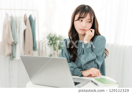 A young Asian businesswoman who is depressed, thinking, and worried while looking at a computer (depressed, lonely) 129112329