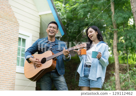 Musical joy. Young couple singing and playing guitar outdoors, enjoying each other's company. Musical joy. Young couple singing and playing guitar outdoors, enjoying each other's company. 129112462