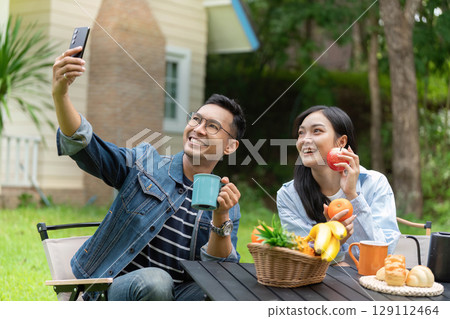 Joyful couple enjoying outdoor moments with fruits and drinks 129112464