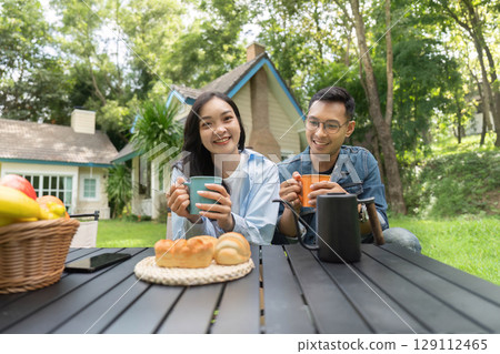 Joyful Gathering. Friends sipping beverages and enjoying snacks in a sunny garden. 129112465