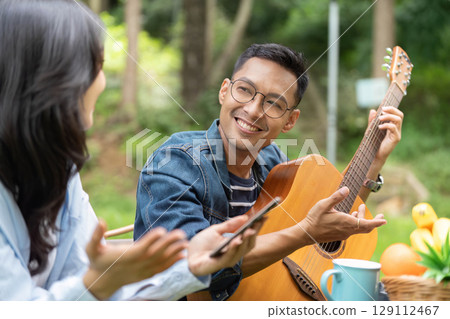Joyful moments. Young couple enjoying music and conversation outdoors. Joyful moments. Young couple enjoying music and conversation outdoors. 129112467