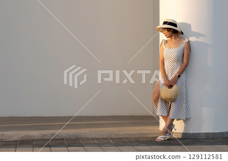 Woman in Polka Dot Dress Leans Against Lit Pavilion Column 129112581