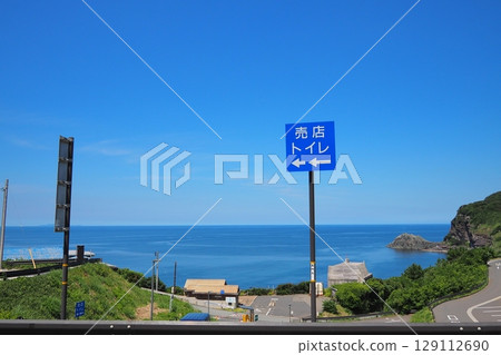 沿著蔚藍大海蜿蜒的道路。藍色的指示牌指示著商店和衛生間的位置。 129112690