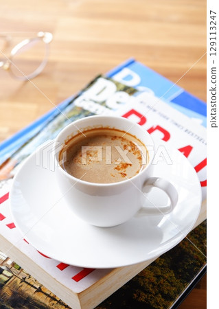 一個人一邊喝著現煮的咖啡一邊放鬆並享受一本書的圖片。 129113247