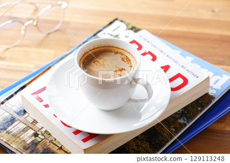 一個人一邊喝著現煮的咖啡一邊放鬆並享受一本書的圖片。 129113248