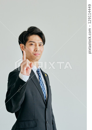 A young lawyer posing with his index finger raised A young lawyer posing with his index finger raised 129114449